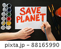 Human hands draw poster with paints and brush on blank sheet with call to save the planet. Rally, appeal, picket 88165990