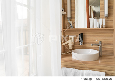 Bathroom in hotel room with window, sink, faucet, face care set and mirror Bathroom in hotel room with window, sink, faucet, face care set and mirror 88166030