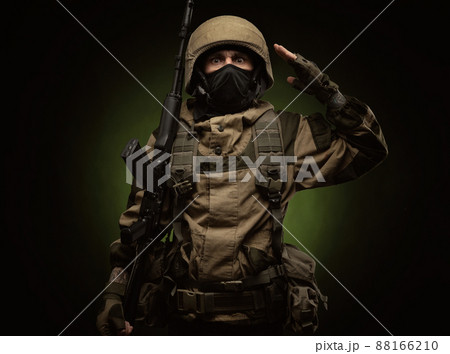 a Russian soldier in a helmet in military clothes with a Kalashnikov assault rifle on a dark background in the studio a Russian soldier in a helmet in military clothes with a Kalashnikov assault rifle on a dark background in the studio 88166210