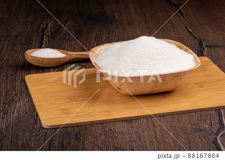 White sugar in wooden bowl and spoon over wooden background. White sugar in wooden bowl and spoon over wooden background. 88167804