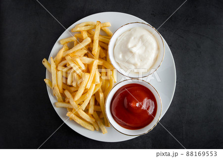 Appetizing crispy fries in plate on a black background. Hot american fast food. Appetizing crispy fries in plate on a black background. Hot american fast food. 88169553