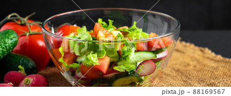 Fresh vegetable salad in a glass bowl on dark background. Vegan organic food, seasonal summer dish. Fresh vegetable salad in a glass bowl on dark background. Vegan organic food, seasonal summer dish. 88169567