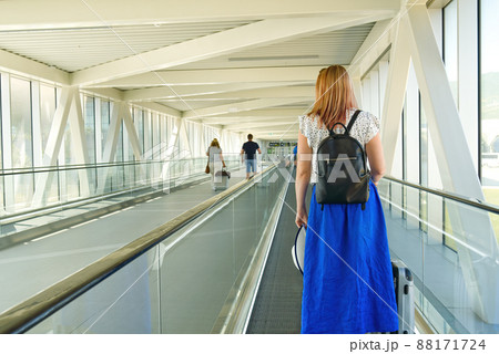Young woman 40s no face with a suitcase riding escalator in airport terminal. Safety travelling alone Covid-19 time 88171724