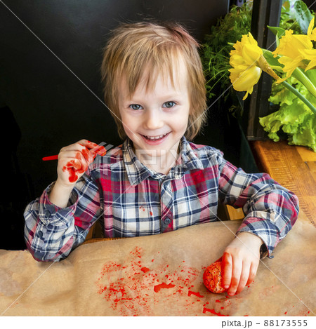 The child preparing for Easter. Paint eggs. Red paint egg. The child preparing for Easter. Paint eggs. Red paint egg. 88173555