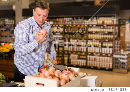 Confident customer choosing onions at grocery store Confident customer choosing onions at grocery store 88174058