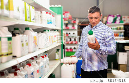Man choosing liquid fertilizer in plastic bottle in hypermarket 88174318