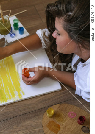 Creative painter in working process. Artist workplace, hobby, craft tools. Artist female canvas painting. Professional young woman painter draws in the workshop Creative painter in working process. Artist workplace, hobby, craft tools. Artist female canvas painting. Professional young woman painter draws in the workshop 88174912