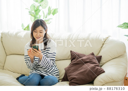 ソファに座りながらスマホを見る30代女性 ソファに座りながらスマホを見る30代女性 88176310