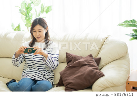 ソファに座りながらスマホ動画を見る30代女性 ソファに座りながらスマホ動画を見る30代女性 88176311
