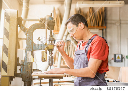 Focused carpenter drilling steel in professional workshop 88176347