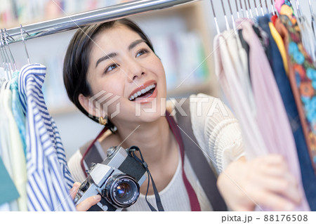 オフィスのハンガーラックの衣装を手にとって写真を撮ろうとする若い女性ファッションエディター 88176508