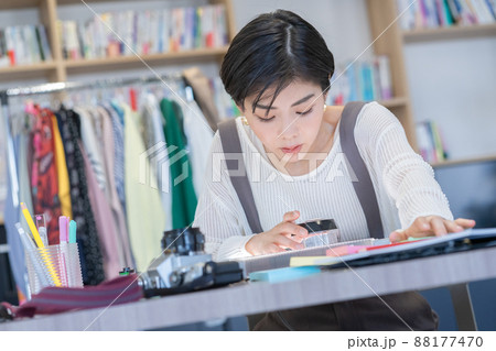 デスクでルーペで写真のネガを見る若い女性ファッションエディター デスクでルーペで写真のネガを見る若い女性ファッションエディター 88177470