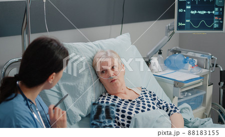 Woman nurse holding x ray scan to old patient for diagnosis and results. Medical assistant showing radiography to elder woman with disease for healthcare laying in hospital ward bed. Woman nurse holding x ray scan to old patient for diagnosis and results. Medical assistant showing radiography to elder woman with disease for healthcare laying in hospital ward bed. 88183155