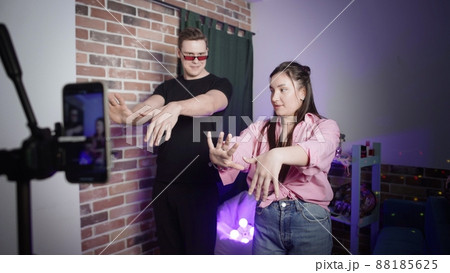 A guy and a girl dance on the camera of a smartphone standing on a tripod. Social network. Blogger A guy and a girl dance on the camera of a smartphone standing on a tripod. Social network. Blogger 88185625