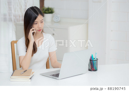 Young asian woman talking phone and work from home with laptop computer. Young asian woman talking phone and work from home with laptop computer. 88190745