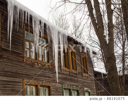 Frozen transparent icicles hang on the edge of the roof. Frozen transparent icicles hang on the edge of the roof. 88191075