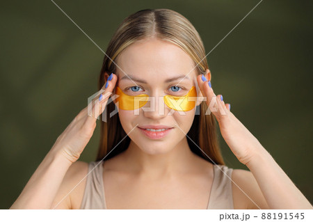 Close up of blonde caucasian girl face with natural no makeup look and white smile. Silicone under eye patches. Using skincare products from dark circles. 88191545
