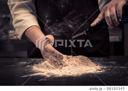 The chef makes dough for pasta on a wooden table The chef makes dough for pasta on a wooden table 88193345
