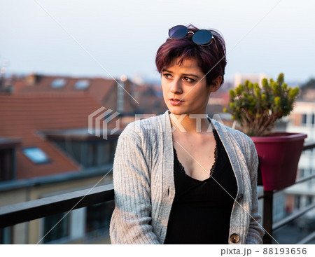 Fashion portrait of a 23 year old white woman with short, dyed hair standing on a terrace 88193656