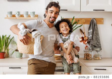 Happy father and son with laundry in kitchen Happy father and son with laundry in kitchen 88193886