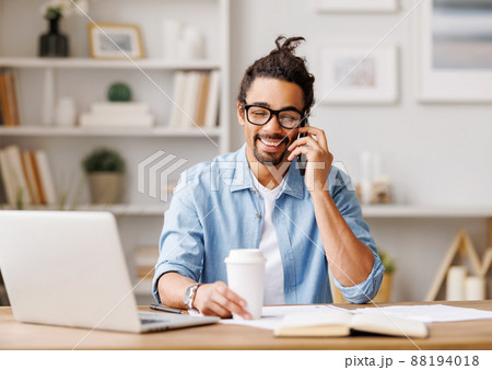 Positive black freelancer talking on smartphone at home 88194018
