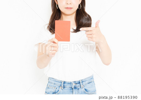 白い背景の前に立ってレッドカードを見せるTシャツを着ている若い女性 88195390