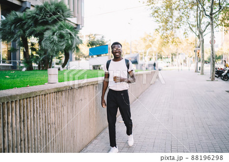 Cheerful African American tourist walking on street with coffee 88196298