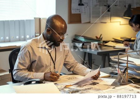 Young FBI agent looking through criminal profiles and making notes Young FBI agent looking through criminal profiles and making notes 88197713