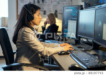 Side view of young Hispanic female operator of surveillance system 88197743