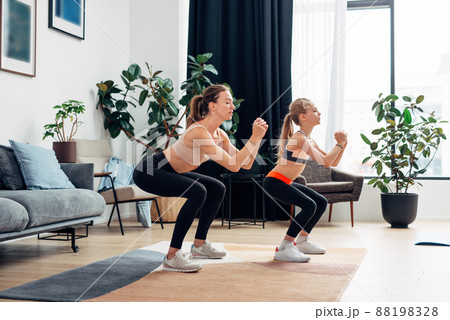 Mother and daughter doing squats. Home training. 88198328