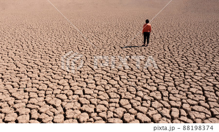 Silhouette of a man on a sandy cracked empty not fertile land during a drought. The concept of ecological catastrophe on the planet. Silhouette of a man on a sandy cracked empty not fertile land during a drought. The concept of ecological catastrophe on the planet. 88198374