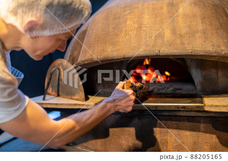 A man making fire in the oven in italian bakery A man making fire in the oven in italian bakery 88205165