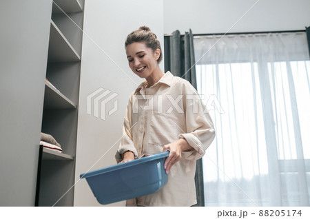 Young dark-haired woman preparing clothes for washing Young dark-haired woman preparing clothes for washing 88205174