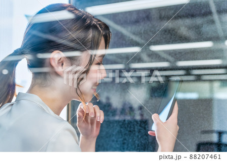 フリーアドレスオフィスの防音電話ボックスで電話をする女性 フリーアドレスオフィスの防音電話ボックスで電話をする女性 88207461