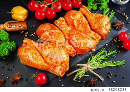Convenience food, precooked.Raw Marinated chicken meat legs with spices for cooking for BBQ dark background. Top view. 88208233