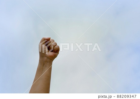 Clenched fist up against the blue sky. Woman's hand of independence and freedom from violence Clenched fist up against the blue sky. Woman's hand of independence and freedom from violence 88209347