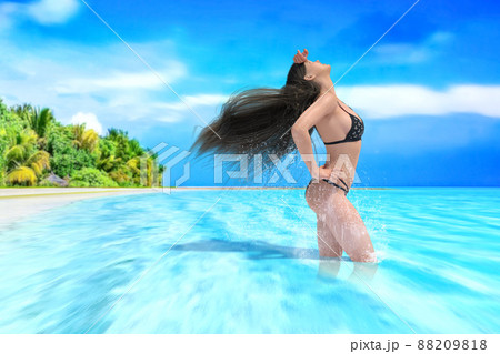 綺麗な青い南国の海にビキニ姿で髪をなびかせて空を見上げる女性 88209818