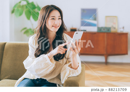 ソファに座ってスマホを見る女性 88213709