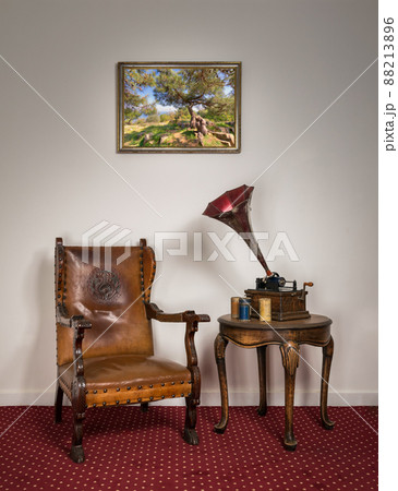 Retro ornate armchair, old phonograph, cylinders on round coffee table 88213896
