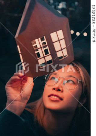 A Woman is looking at festive decoration light house lamp in winter festival new year celebration. 88213931