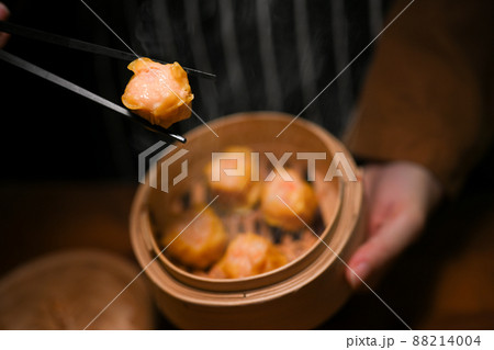 Women eating steamed shrimp dumplings with chopsticks 88214004