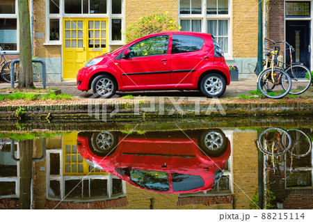 Red car on canal embankment in street of Delft. Delft, Netherlands 88215114