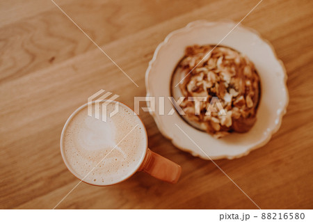 A cup of coffee and a fragrant bun on a wooden table in a city cafe 88216580