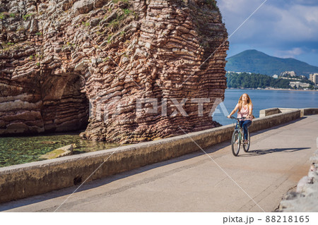 Woman tourist on a bicycle explores Budva in Montenegro. Cycling in Montenegro concept Woman tourist on a bicycle explores Budva in Montenegro. Cycling in Montenegro concept 88218165