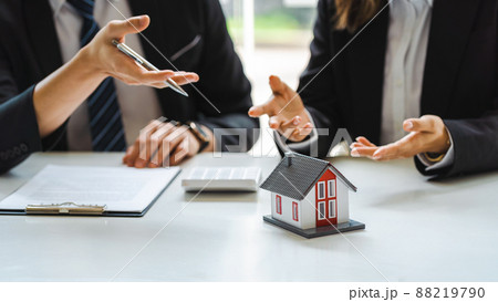 Businessman signs contract behind home architectural model. 88219790