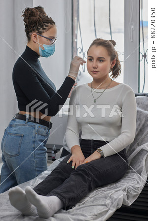 Stretched lobe piercing, grunge concept. Pierced woman ear with black plug tunnel. industrial and rook. 88220350