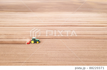 Lonely tractor on agricultural field with rows of plowed soil Lonely tractor on agricultural field with rows of plowed soil 88220371