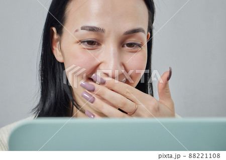 Closeup of a young woman's visage with piercing septum hanging from her nose. 88221108