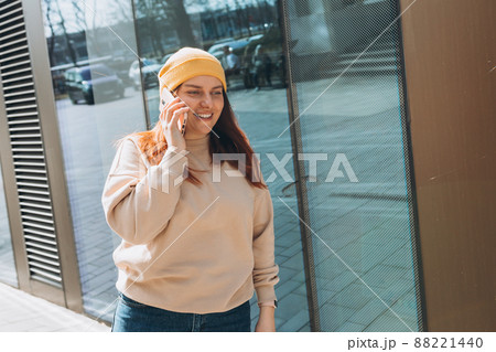 Beautiful smiling female in yellow hat talking on Phone standing outdoors. Phone Communication. Happy cheerful young woman walking on city street, Urban lifestyle concept. Traveler Beautiful smiling female in yellow hat talking on Phone standing outdoors. Phone Communication. Happy cheerful young woman walking on city street, Urban lifestyle concept. Traveler 88221440