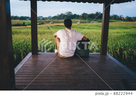 Unrecognizable man sitting in wooden alcove in countryside Unrecognizable man sitting in wooden alcove in countryside 88222944